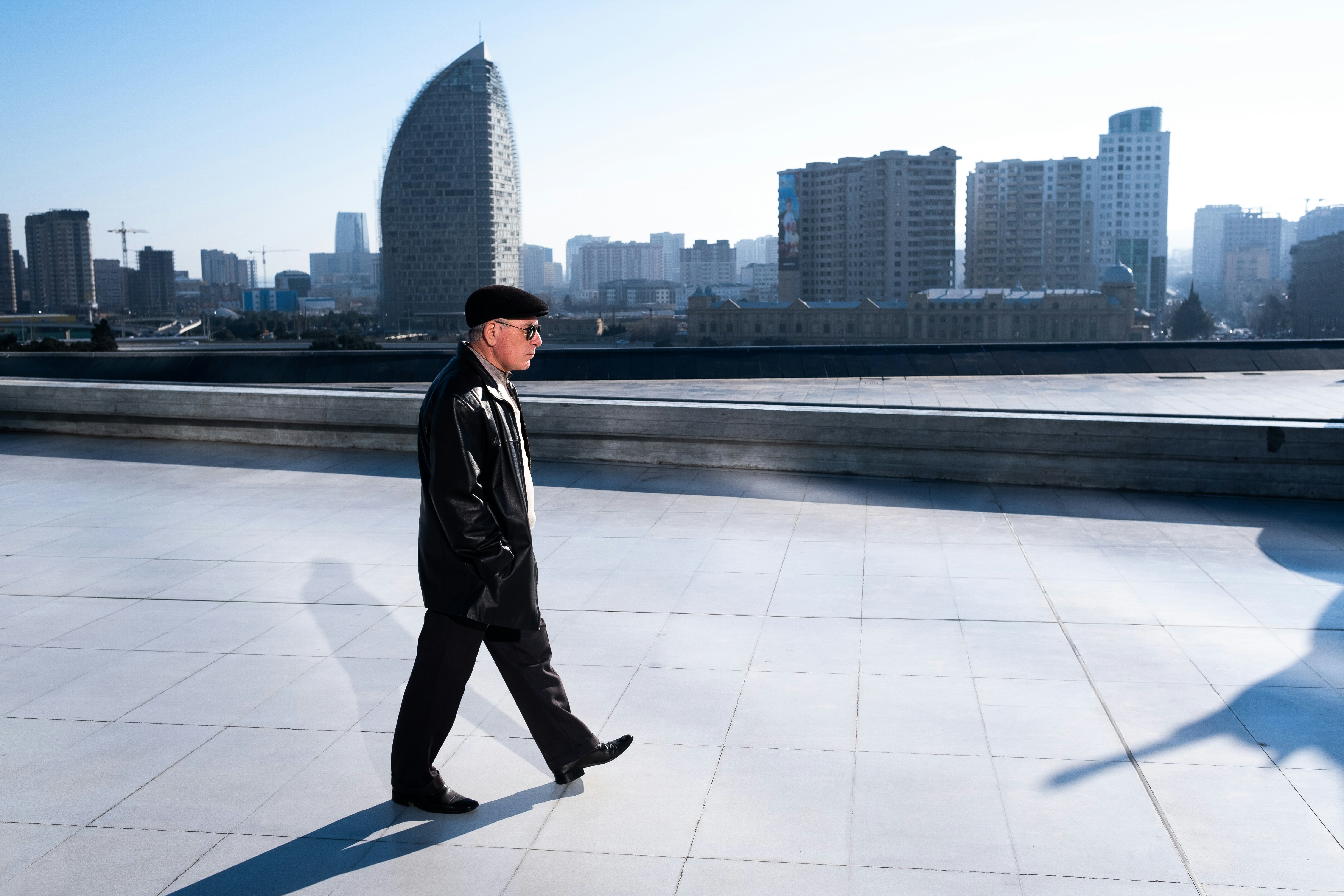 man in black leather jacket standing on white floor tiles during daytime